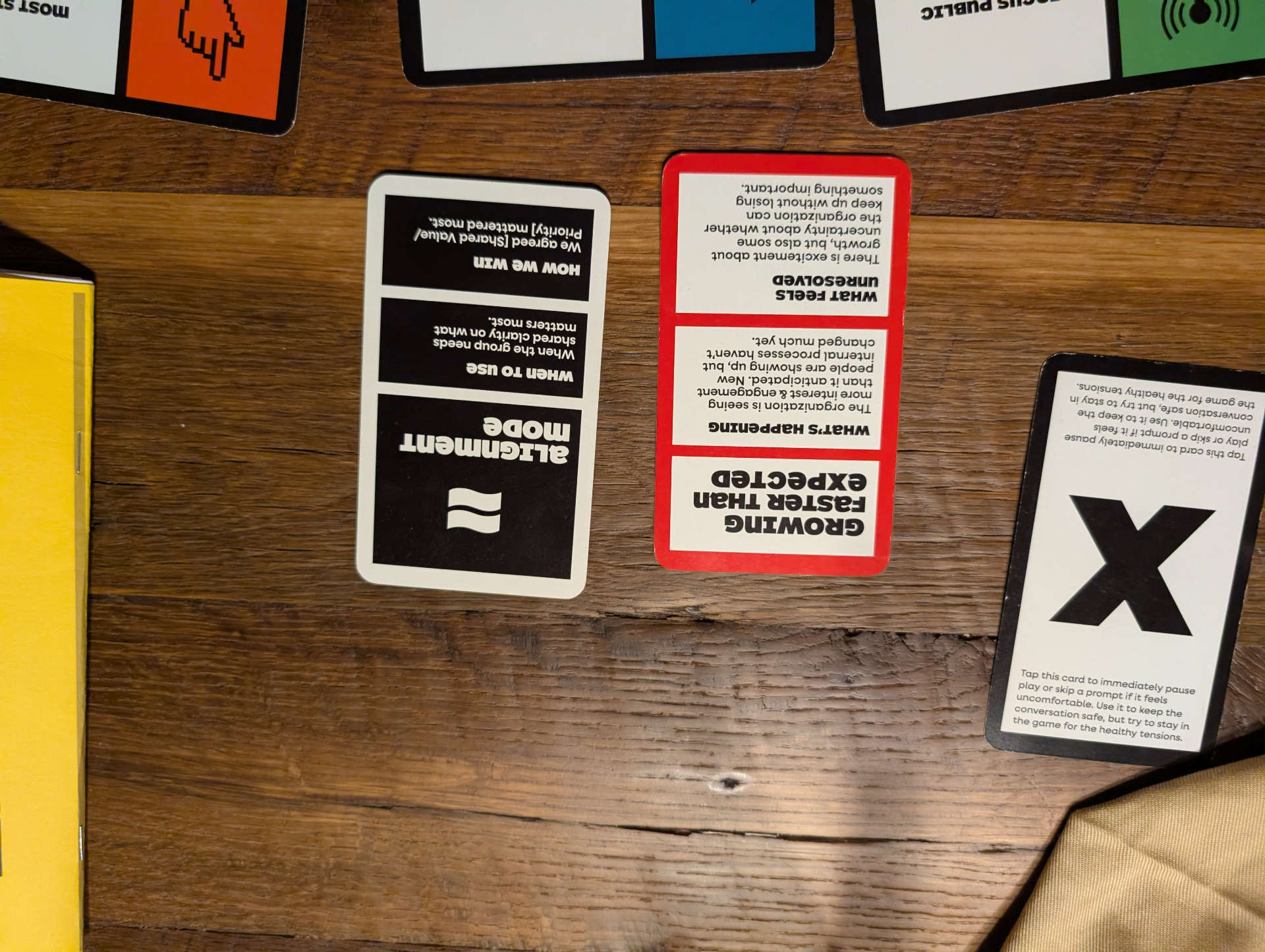 Alignment Mode card sitting beside a red Growing Faster Than Expected scenario card, with the black X pause card at the ready.